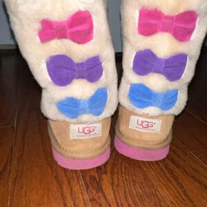 Girls UGG boots with colorful bows on the back.